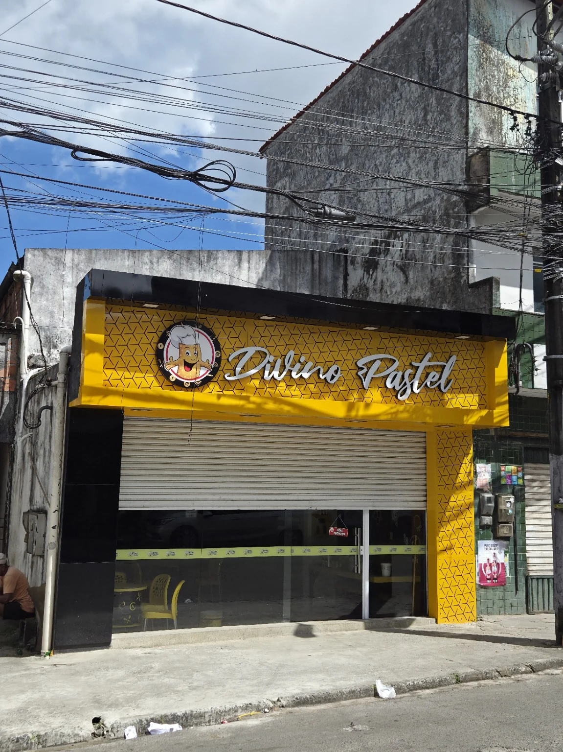 Fachada amarela e preta da Divino Pastel com logo e letras em relevo