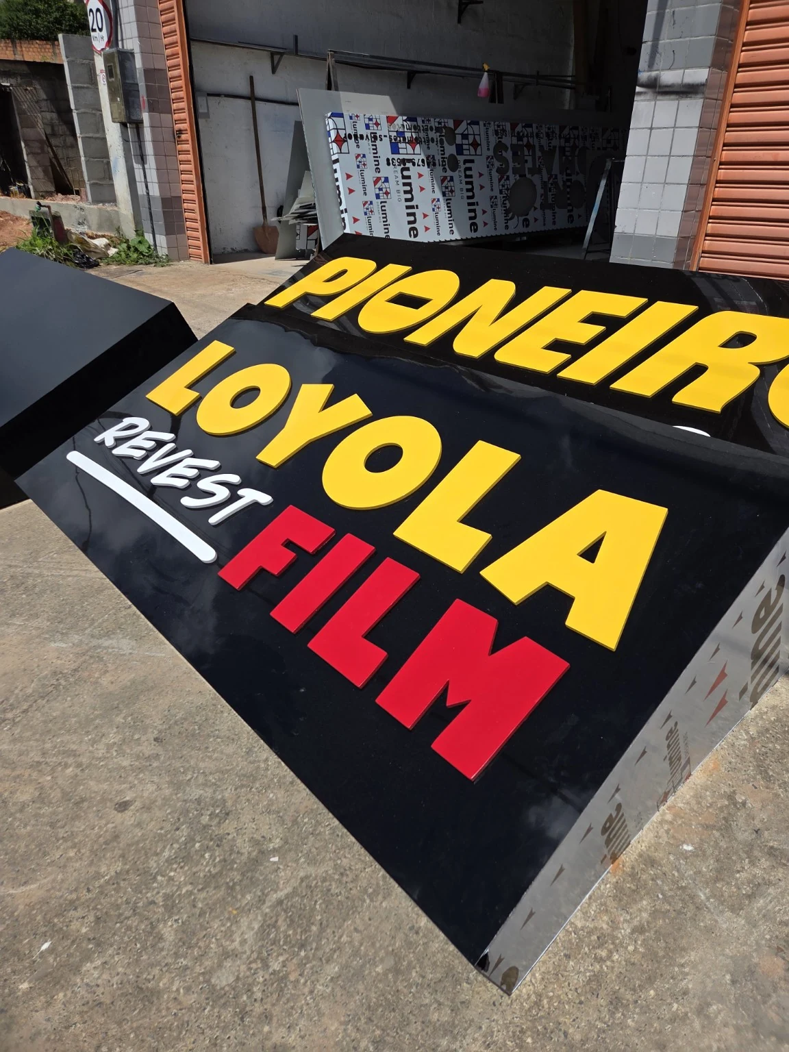 Letreiro preto com letras amarelas, brancas e vermelhas da Loyola Film durante a fabricação